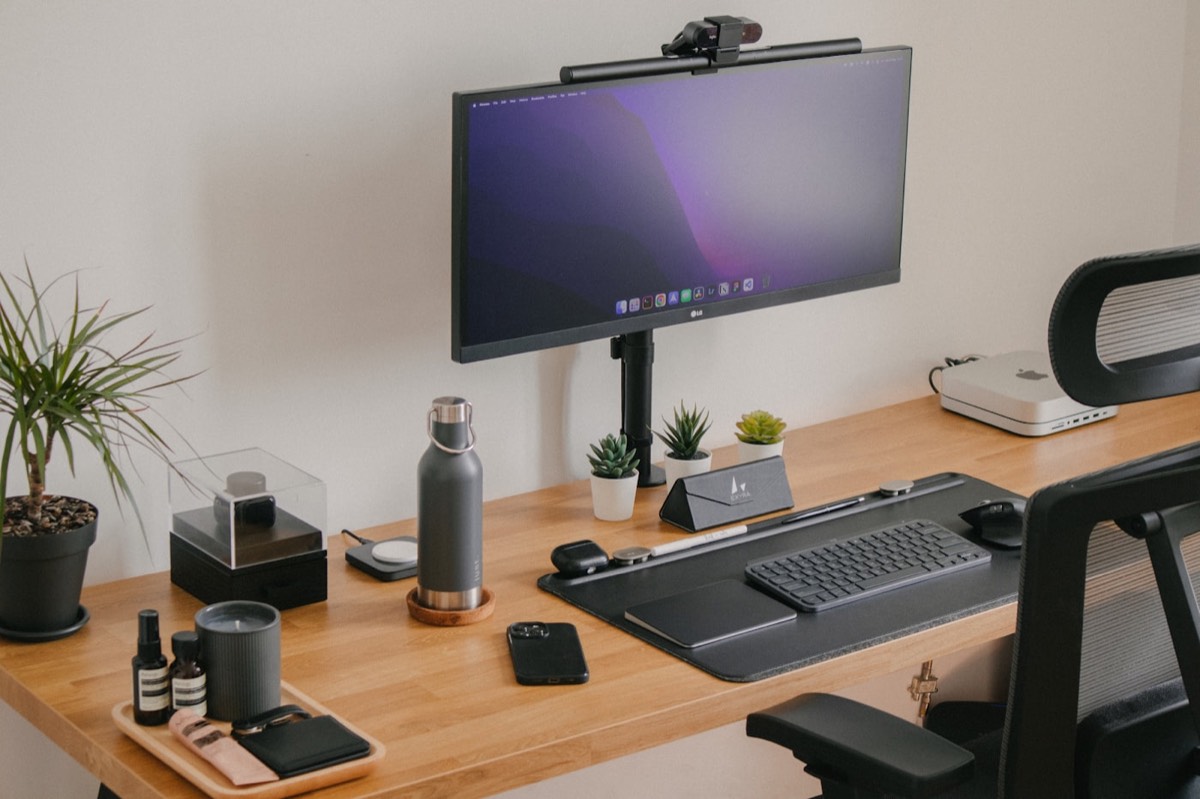 Clean Mac workstation with monitor, keyboard, and accessories on a wooden desk